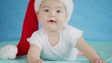 Mutlu Noeller ve mutlu yıllar, çocukluk, tatil konsepti yakın çekim. Noel Baba şapkalı yeni doğmuş 3 aylık bebek karnında emekliyor..