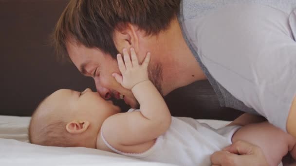 Chiudere di padre nero millenario sdraiato sul letto a giocare con il suo bambino appena nato dauther. — Video Stock