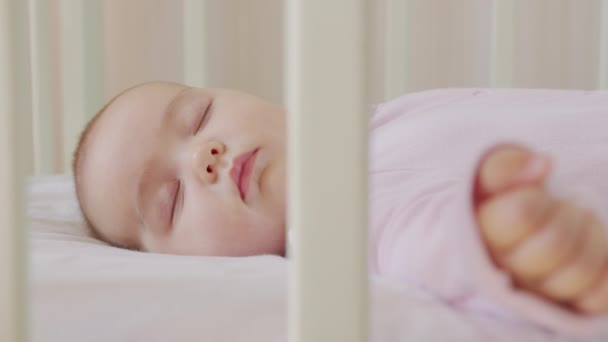Aranyos kisbaba édesen alszik a bölcsőjében, és színes álmokat lát a hálószobában, miközben alszik.. — Stock videók