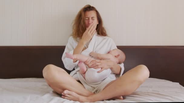 Bebekleri kucağında tutarken esnemekten yorulmuş anne. — Stok video