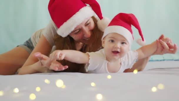 Smiling Santa child lying in santa claus costume, in red hat with mother. — Stock Video