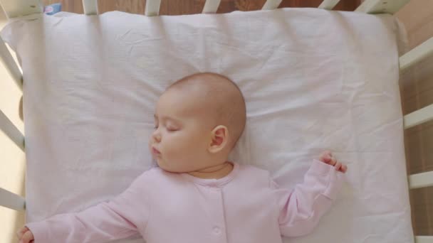 かわいい赤ちゃんは彼のベビーベッドで甘い眠り、寝室でカラフルな夢を見ます. — ストック動画
