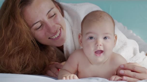 Ευτυχισμένη μητέρα και το νεογέννητο μωρό της. Ξεκουραζόμαστε στο κρεβάτι μαζί. Η έννοια της μητρότητας. Η πατρότητα. Μητρότητα όμορφη ευτυχισμένη οικογένεια αργή κίνηση. — Αρχείο Βίντεο