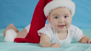 Mutlu Noeller ve mutlu yıllar, çocukluk, tatil konsepti yakın çekim. Noel Baba şapkalı yeni doğmuş 3 aylık bebek karnında emekliyor..