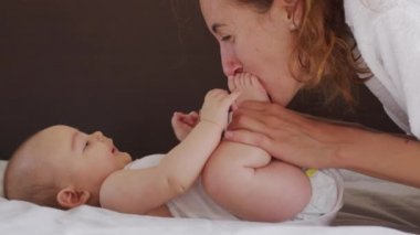 Genç annenin otantik yakın plan çekimi bir sabah bebek odasında yeni doğmuş bebeğiyle oynuyor. Çocuk, bebek, ebeveynlik, çocukluk, hayat, annelik, annelik kavramı.