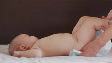 Annem geceleri bebek bezi değiştiriyor. Kafkasyalı güzel bir anne çocuğunun bezini değiştiriyor. Yakın plan..