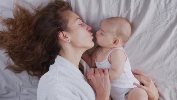 Bakıcı anne ve bebek sabahları yatakta oynuyorlar.. — Stok video