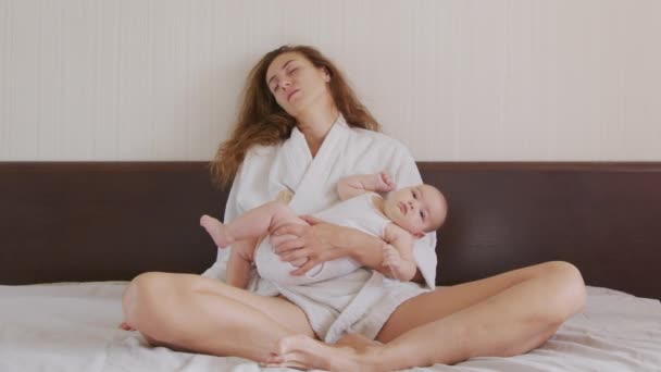 Trött mamma gäspande medan du håller och vårdar spädbarn. — Stockvideo