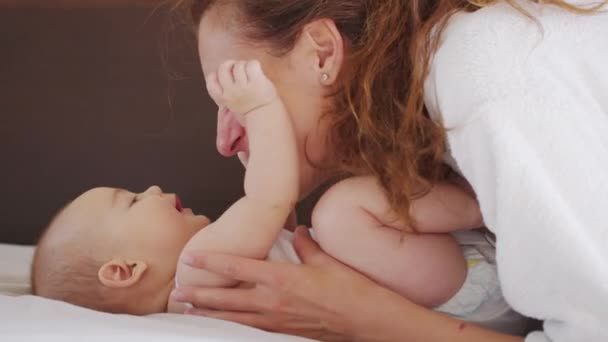 Yakın bir anne bebeğini nazikçe öpüyor ve yeni doğmuş çocuğuyla olan bağını paylaşan bebeğe neşeyle anneciğini seviyor. sağlıklı çocuk bakımı. — Stok video