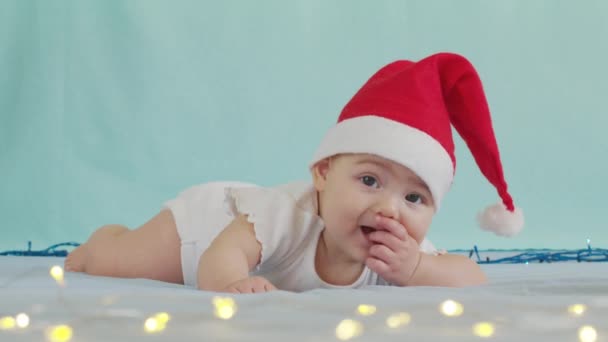 God Jul och Gott Nytt År, Barndom, Semester koncept närbild. 3 månader gammal nyfödd baby i Santa Claus hatt på magen kryper. — Stockvideo