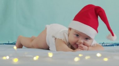 Mutlu Noeller ve mutlu yıllar, çocukluk, tatil konsepti yakın çekim. Noel Baba şapkalı yeni doğmuş 3 aylık bebek karnında emekliyor..