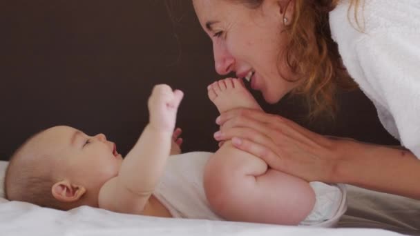 Закройте рот матери, мягко целующей ребенка, наслаждаясь любящей мамой, играючи ухаживающей за малышом дома, делясь общением со своим новорожденным ребенком. здоровый уход за детьми. — стоковое видео