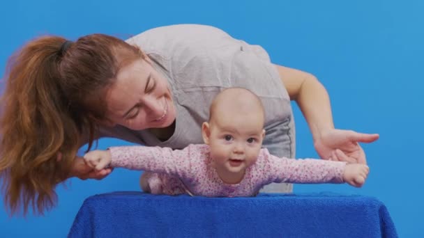 Mama bawi się ze swoją nowo narodzoną córką. Izolacja na niebieskim tle. — Wideo stockowe