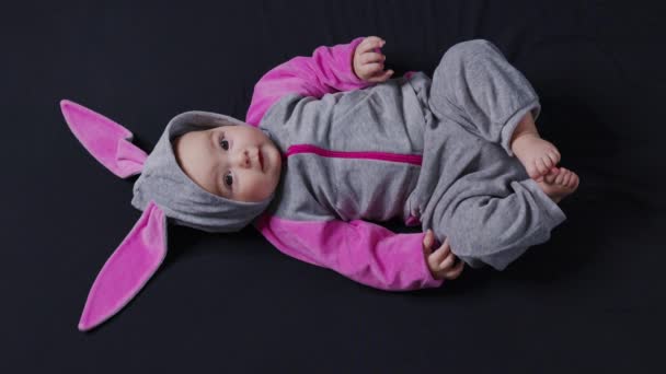 かわいい赤ちゃんの笑顔とカメラを閉じて見て。イースターバニーの衣装の小さな子供、トップビュー. — ストック動画