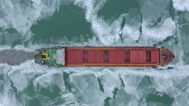 Luchtfoto episch rood schip in de winter vaart door bevroren zee maakt zijn weg. IJsschotel grafisch patroon. Gespecialiseerd schip voor het breken van ijs maakte een expeditie Noordpool, Arctische. — Stockvideo
