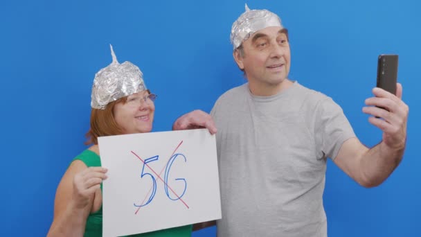 Άντρας και γυναίκα κρατούν πλακάτ χωρίς πινακίδα 5g. διαμαρτυρία ενάντια στην τεχνολογία 5G και την ανάπτυξη κεραίας συμβατό με 5G, ενώ στέκεται στο μπλε φόντο. — Αρχείο Βίντεο