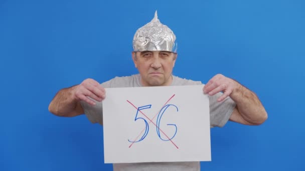 Man met bordje zonder 5g teken. protesteren tegen de inzet van 5G-technologie en 5G-compatibele antennes terwijl ze op een blauwe achtergrond staan. — Stockvideo