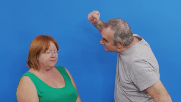 Side view of Indian couple sorting things out. Spouses quarrel, emotionally gesticulating. Man doing aggressive slap gesture. Isolated on blue background. — Stock Video