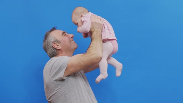 Jeu drôle et rire du vieil homme caucasien et bébé fille dans le confort domestique. Peau ridée du grand-père ou du père chevelu gris dans un éclairage naturel décontracté. — Video