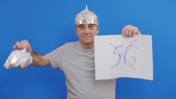 Elinde 5 G işareti olmayan bir pankart tutan adam. 5G teknolojisini ve 5G uyumlu anten konuşlandırmasını protesto ederken mavi arka planda duruyor.. — Stok video