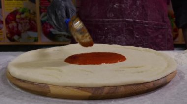 Chef 'in Yakın Çekimi Pizza Hamuru üzerine domates sosunu geleneksel İtalyan pizzasında Metal Ladle ile yayıyor..
