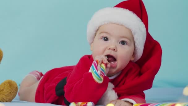 Καλά Χριστούγεννα και ευτυχισμένο το νέο έτος, παιδική ηλικία, διακοπές έννοια close-up. 3 μηνών νεογέννητο μωρό στον Άγιο Βασίλη καπέλο στην κοιλιά του σέρνεται. — Αρχείο Βίντεο