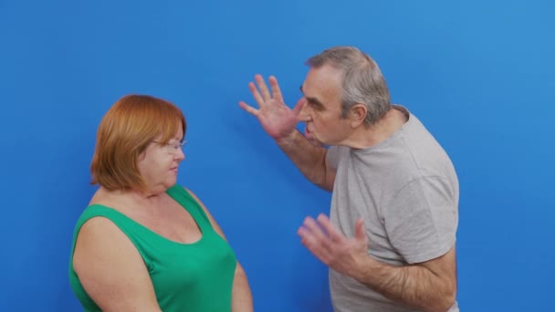 Couple quarreling on blue background. Aged couple quarreling. Conflict, negative emotions. — Stock Video