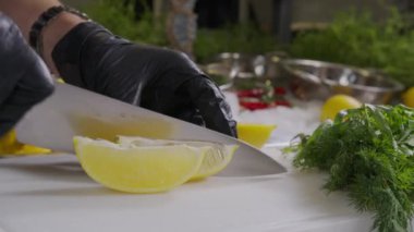 Tahta kesme tahtasıyla kadın limonu ikiye böler. Manzarayı kapat. Yemek pişirmek için sağlıklı malzeme. Limon dilimliyorum. Ekşi meyve.