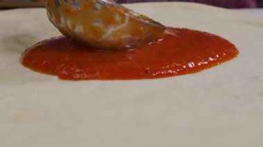 İtalyan pizzası pişiren bir aşçının yakın görüntüsü. Masada pizza yapma süreci. Mutfak masasında taze hamur. İzolasyon döneminde evde yemek pişirmek, 2020 salgını. Evde kal konsepti.