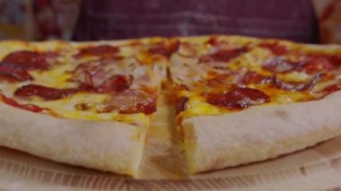 Yuvarlak bir bıçakla pizza kesmek. Lezzetli pizzanın parçalara ayrıldığı yakın plan çekimler. Yavaş çekimde, pizzayı dilimleyen kişinin kesiciyle yavaş çekimde yakın plan görüntüsü..