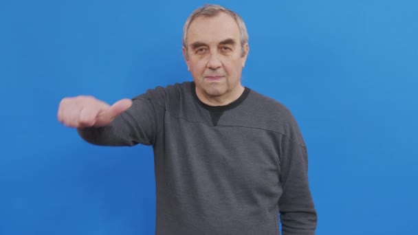 Hombre mayor mostrando sus pulgares hacia arriba aprobando su elección. Estudio de tiro en la pared azul. — Vídeos de Stock