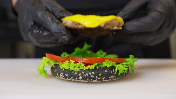 Close up shot of large tasy burger with beef steak, iceberg cabbage, tomatoes, melted cheese. Cooking at home during isolation period, pandemic 2020. Stay home concept. — Wideo stockowe