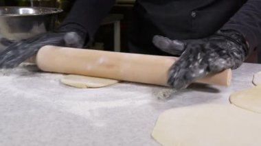 Siyah eldivenli yakın plan çekimler fırın şefi hamur üzerine un sürüyor, arka planda izole edilmiş 4K görüntü. İzolasyon döneminde evde yemek pişirmek, 2020 salgını. Evde kal konsepti.