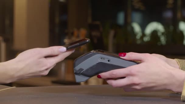 Een close-up. Klantvrouw betaalt voor koffie met behulp van NFC-technologie met telefoon en creditcard, contactloze betaling met student meisje vrouw na coronavirus quarantaine pandemie. — Stockvideo