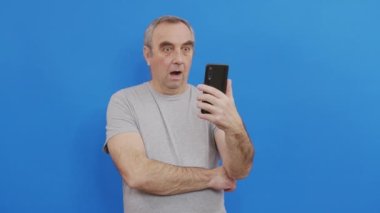 Mutlu yaşlı adam elinde akıllı bir telefonla internetten cep telefonuyla arıyor..