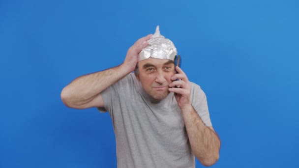 El hombre asustado en un sombrero de papel de aluminio ondeó las ondas 5G. Protección contra la radiación de la torre 5G. Miedo irracional a un problema inexistente. Casco protector de aluminio para el cerebro de los extraterrestres. — Vídeos de Stock