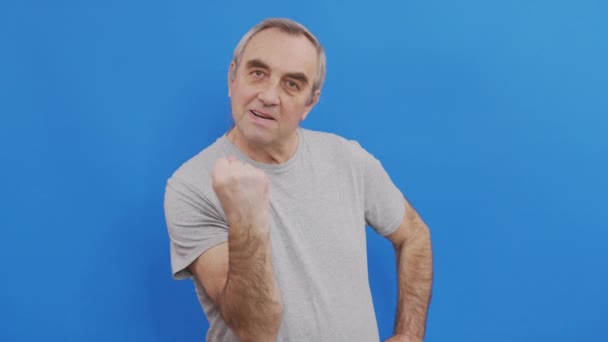 Старший чоловік показує кулак до камери, агресивний вираз обличчя . — стокове відео