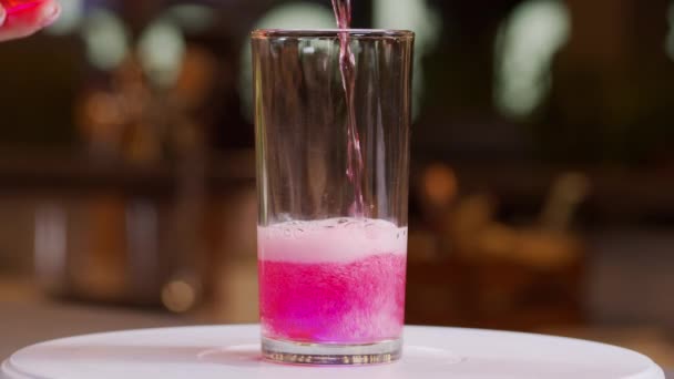 Tuang minuman ringan merah muda ke dalam gelas, close-up gerak lambat saku 6K. — Stok Video