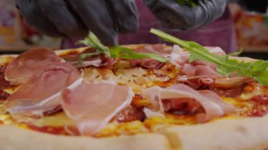 Pişmiş pizzaya taze kişniş serpiştiren bir şefin yakın plan görüntüsü. Yeni pişmiş pizzaya garnitür serpiyorum. İzolasyon döneminde evde yemek pişirmek, 2020 salgını. Evde kal konsepti.