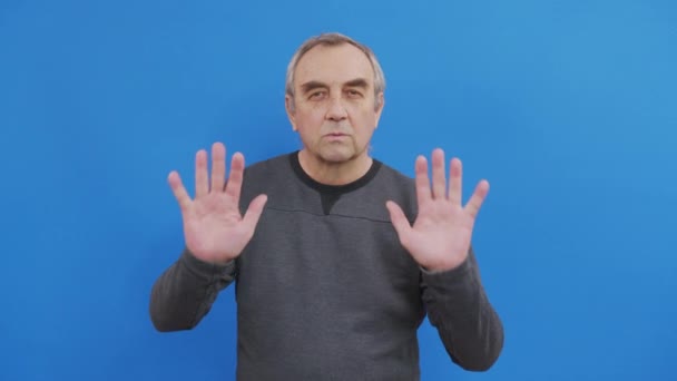 Dissatisfied elderly gray-haired mustache man in casual t-shirt isolated on bright blue color background studio. People lifestyle concept. Showing stop gesture with palm hands. — Stock Video