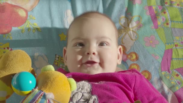 Baby meisje spelen met het ontwikkelen van speelgoed liggend in bed. Bovenaanzicht. — Stockvideo