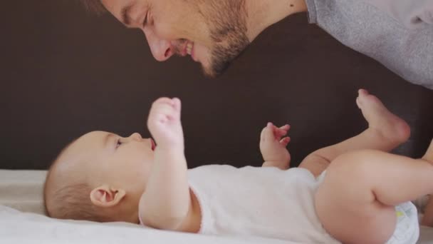 Chiudere di padre nero millenario sdraiato sul letto a giocare con il suo bambino appena nato dauther. — Video Stock