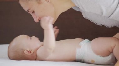 Genç annenin yakın plan çekimi, yeni doğmuş bebeğiyle bir sabah kreşte oynayacak. Çocuk, bebek, ebeveynlik, çocukluk, hayat, annelik kavramı.