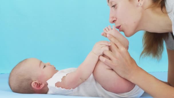 Tender kärleksfull mamma kysser bindning med söt liten flicka dotter liggande på sängen. Glad omtänksam mamma och rolig bedårande spädbarn son leka ha kul i sovrummet. — Stockvideo