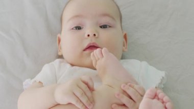 Küçük oğlan bacaklarıyla oynuyor. Isır ve ayak parmaklarını em..