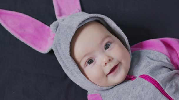 Sevimli bebek gülümsüyor ve kameraya yakından bakıyor. Tavşan kostümü giymiş küçük bir çocuk.. — Stok video