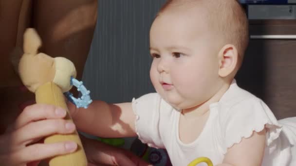 Lustiges fröhliches Baby-Mädchen krabbelt mit Kinderzähnen auf dem Bauch und wiegt sich auf Knien im sonnendurchfluteten Kinderzimmer. — Stockvideo