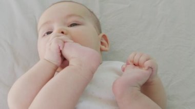 Küçük oğlan bacaklarıyla oynuyor. Isır ve ayak parmaklarını em..