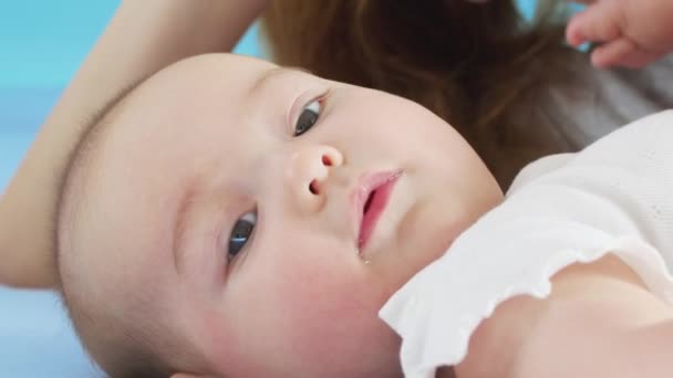 Bebê sorridente bonito: Um bebê lindo jaz na cama e sorri para a câmera com um bom fundo de foco suave. — Vídeo de Stock