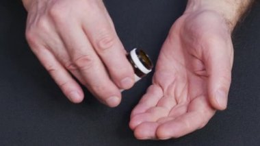 Yetişkin bir adam elinde ağrı kesici haplarla ilaç şişesinden iki kapsül dolduruyor ilaç, eczane ve tedavi konsepti alıyor..